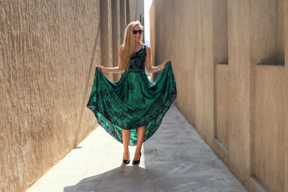 Model twirling an emerald silk dress in a sunlit alley