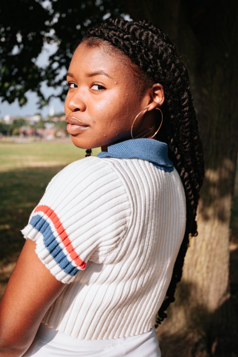 Model wearing a cream ribbed knit polo with stripe trim