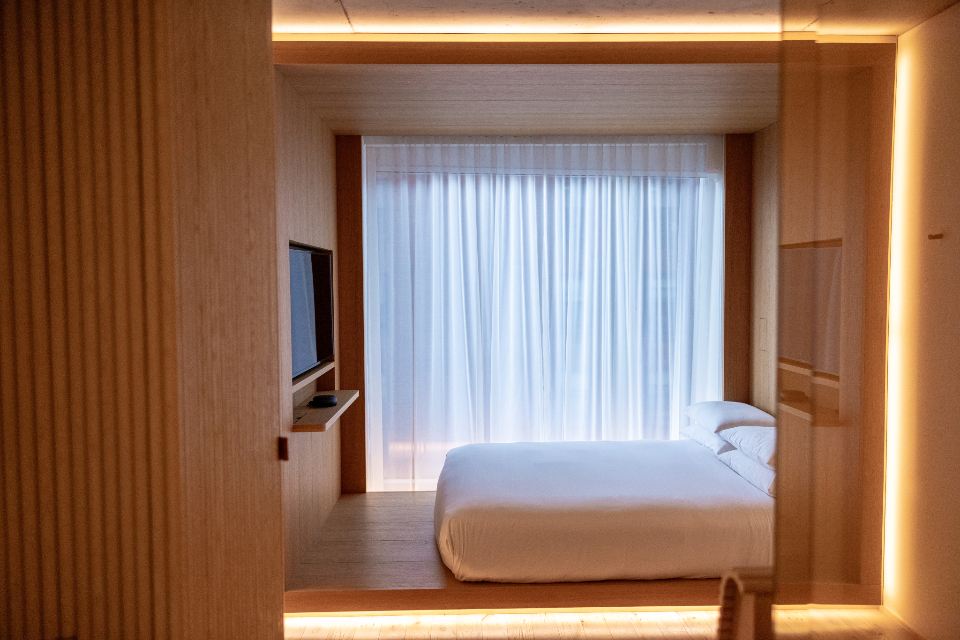 A calm bedroom framed in warm timber with sheer curtains