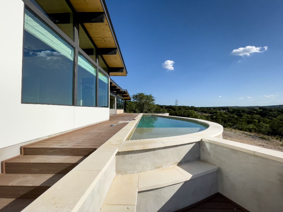 A white modern villa with an infinity pool looking out over green hills
