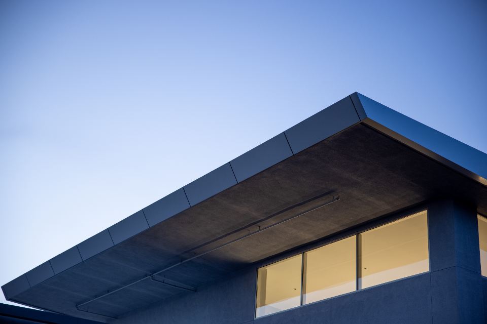 A cantilevered roof edge against a clear blue sky