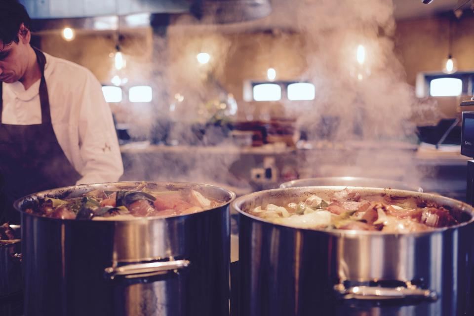 Steam rising from large pots in the restaurant kitchen